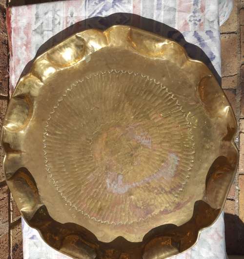 A VINTAGE BRASS TRAY APPROXIMATELY 23INCHES IN DIAMETER IN GOOD CONDITION SOLD AS IS