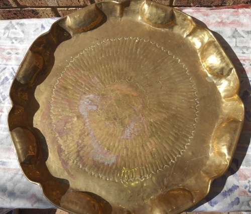 A VINTAGE BRASS TRAY APPROXIMATELY 23INCHES IN DIAMETER IN GOOD CONDITION SOLD AS IS