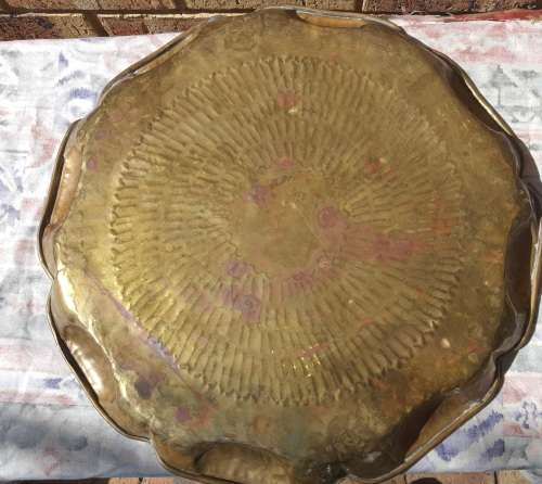 A VINTAGE BRASS TRAY APPROXIMATELY 23INCHES IN DIAMETER IN GOOD CONDITION SOLD AS IS