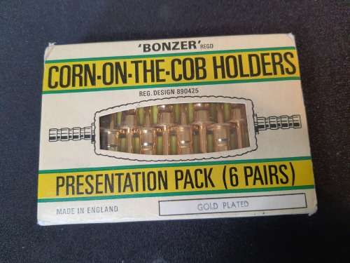 A vintage gold plated corn on the cob holders in its original packaging