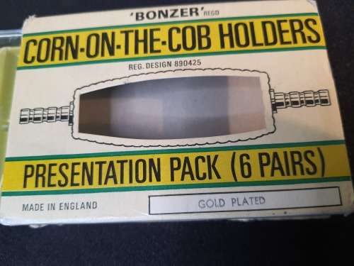A vintage gold plated corn on the cob holders in its original packaging