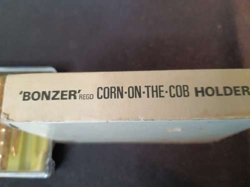 A vintage gold plated corn on the cob holders in its original packaging