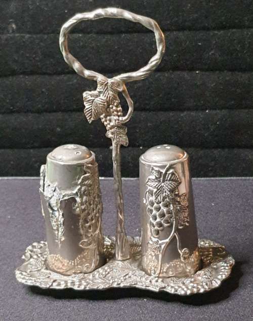 AN ORNATE SILVER PLATED SALT AND PEPPER STAND AND TWO SHAKERS SOLD AS IS