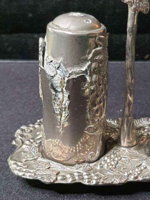 AN ORNATE SILVER PLATED SALT AND PEPPER STAND AND TWO SHAKERS SOLD AS IS