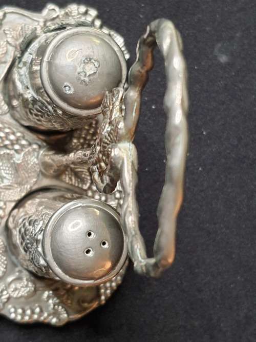 AN ORNATE SILVER PLATED SALT AND PEPPER STAND AND TWO SHAKERS SOLD AS IS