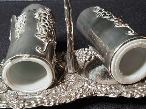 AN ORNATE SILVER PLATED SALT AND PEPPER STAND AND TWO SHAKERS SOLD AS IS