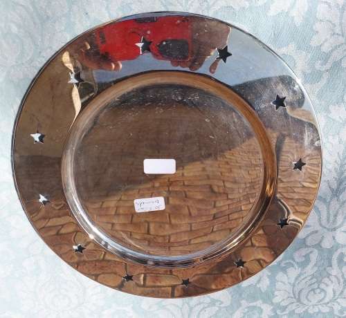 A  ROUND STAINLESS STEEL SERVING TRAY WITH STARS PUNCHED AROUND THE BRIM SOLD AS IS