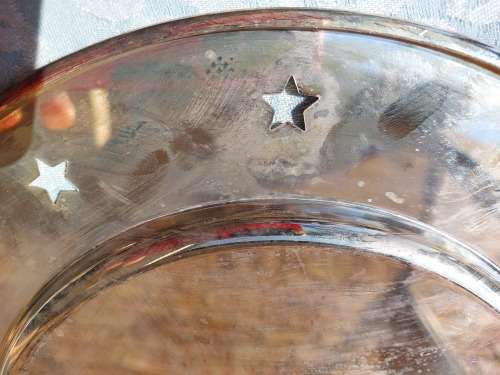 A  ROUND STAINLESS STEEL SERVING TRAY WITH STARS PUNCHED AROUND THE BRIM SOLD AS IS