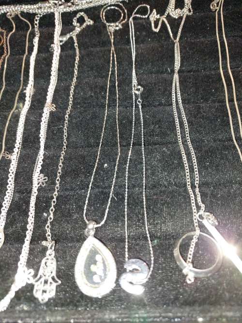 A COLLECTION OF SILVER PLATED AND STAINLESS STEEL NECKLACES WITH PENDANTS SOLD AS IS