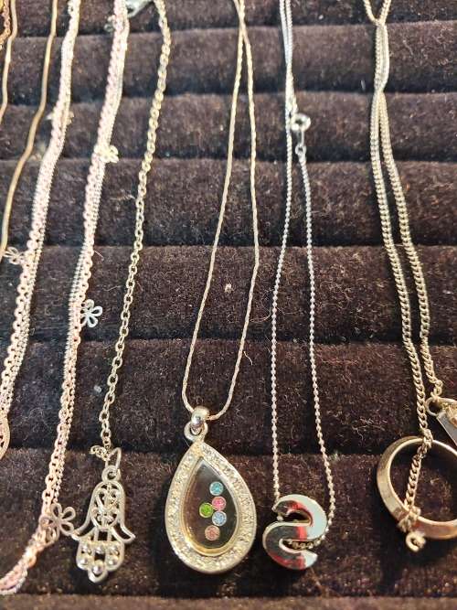 A COLLECTION OF SILVER PLATED AND STAINLESS STEEL NECKLACES WITH PENDANTS SOLD AS IS