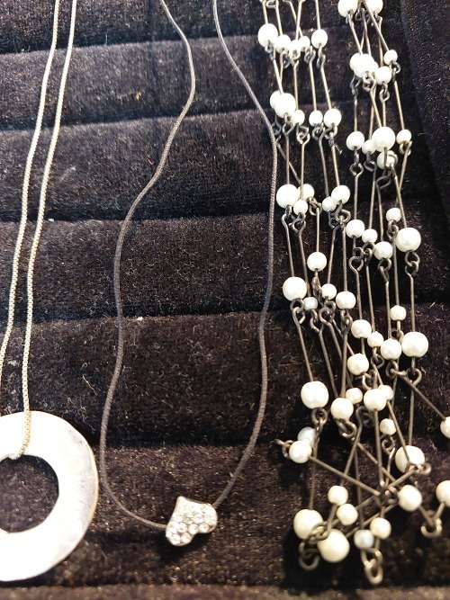 A COLLECTION OF SILVER PLATED AND STAINLESS STEEL NECKLACES WITH PENDANTS SOLD AS IS