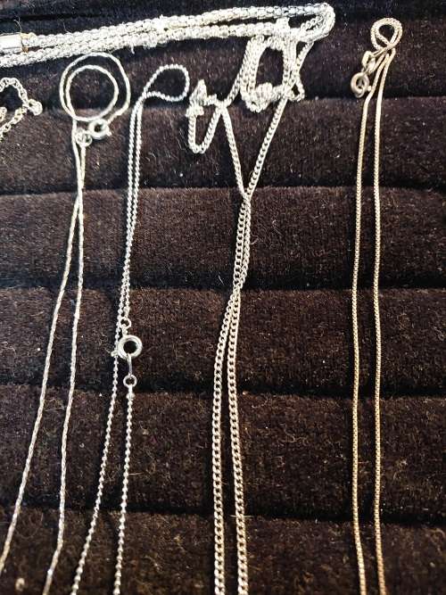 A COLLECTION OF SILVER PLATED AND STAINLESS STEEL NECKLACES WITH PENDANTS SOLD AS IS