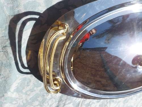 AN OVAL STAINLESS STEEL SERVING PLATTER WITH GOLD TONE HANDLES SOLD AS IS