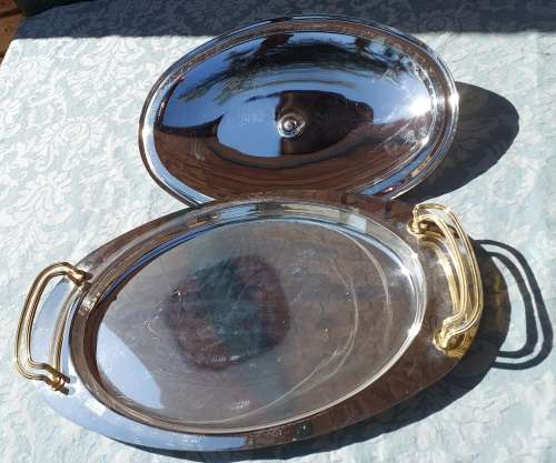 AN OVAL STAINLESS STEEL SERVING PLATTER WITH GOLD TONE HANDLES SOLD AS IS