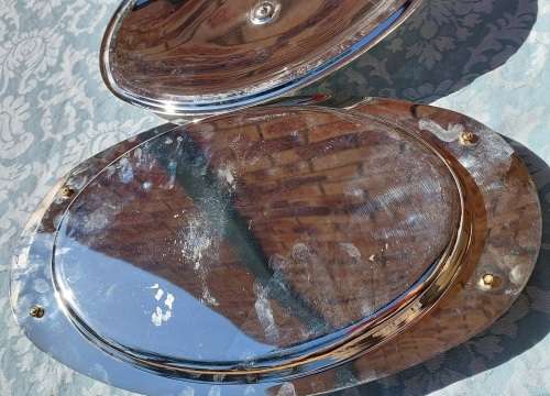 AN OVAL STAINLESS STEEL SERVING PLATTER WITH GOLD TONE HANDLES SOLD AS IS