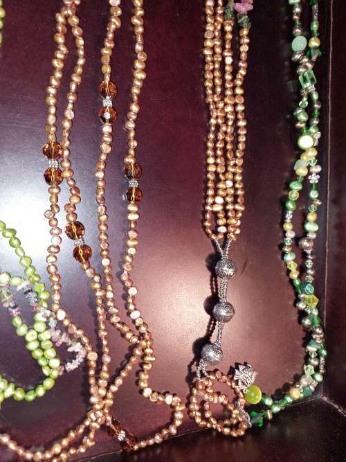 A COLLECTION OF MULTI COLOURED EXTRA LENGTH PEARL NECKLACES SOLD AS IS
