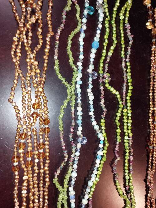 A COLLECTION OF MULTI COLOURED EXTRA LENGTH PEARL NECKLACES SOLD AS IS