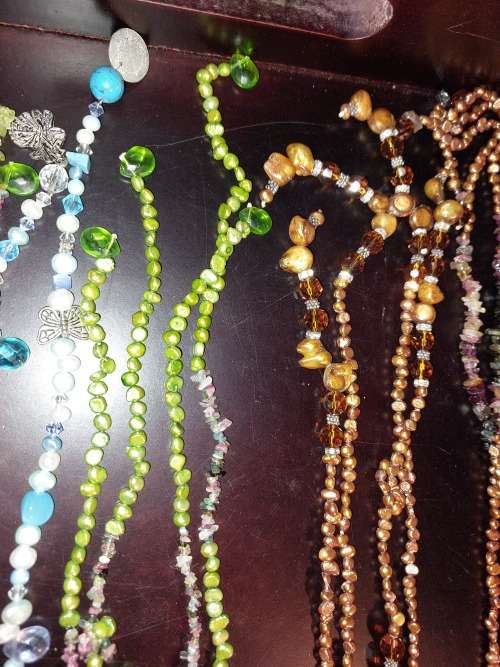 A COLLECTION OF MULTI COLOURED EXTRA LENGTH PEARL NECKLACES SOLD AS IS
