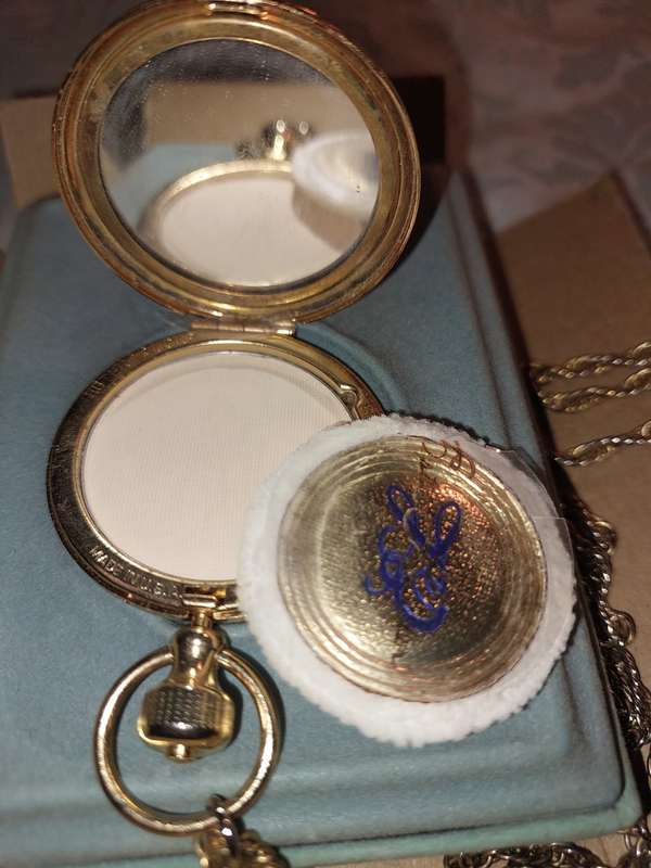 AN ANTIQUE ESTEE LAUDER FILIGREE WATCH STYLE COMPACT GOLD PLATED  WITH CHAIN