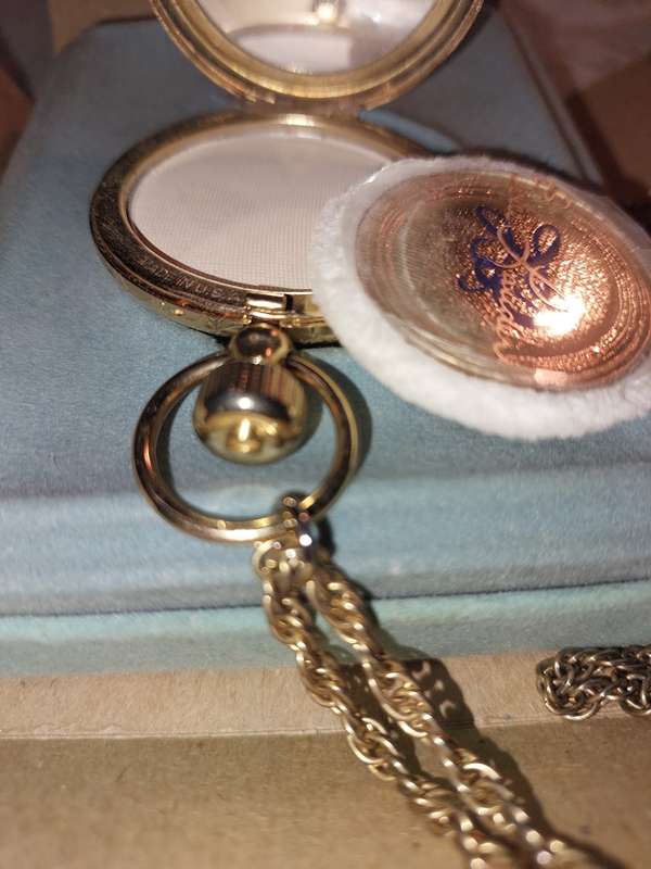 AN ANTIQUE ESTEE LAUDER FILIGREE WATCH STYLE COMPACT GOLD PLATED  WITH CHAIN