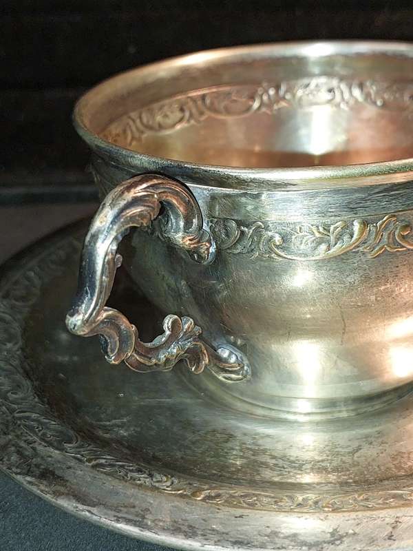A VINTAGE SILVER PLATED TEA CUP AND SAUCER