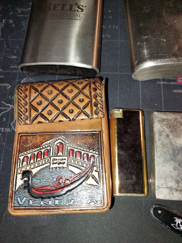 A COLLECTION OF FLASKS CIGARETTE LIGHTERS  POCKET KNIVES AND A LEATHER CIGARETTE HOLDER SOLD AS IS