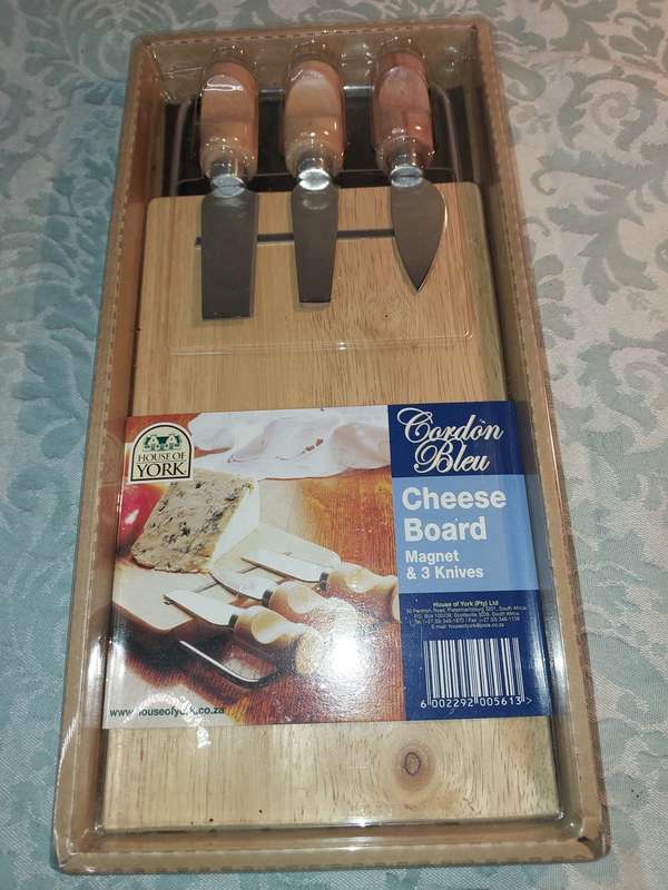 A NEVER BEEN USED GORDON BLU CHEESE BOARD AND THREE KNIVES SOLD AS IS