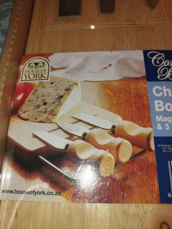 A NEVER BEEN USED GORDON BLU CHEESE BOARD AND THREE KNIVES SOLD AS IS