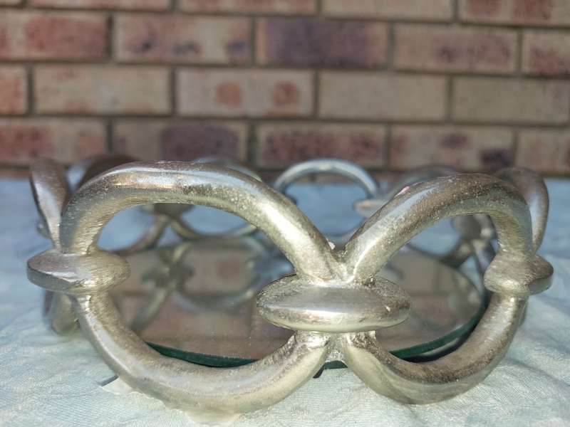 A ROUND CHAIN LINK STYLE ART DECOR SERVING TARY WITH A MIRROR BASE,
