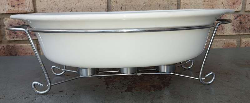 AN OVEN PROOF PORCELAIN CASSEROLE BOWL WITH A STAINLESS STEEL CANDLE STAND WARMER