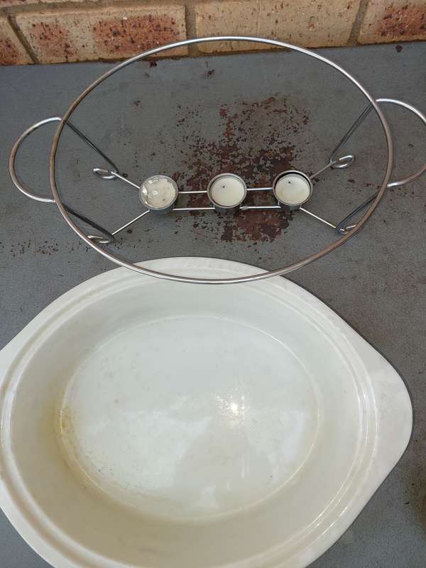 AN OVEN PROOF PORCELAIN CASSEROLE BOWL WITH A STAINLESS STEEL CANDLE STAND WARMER
