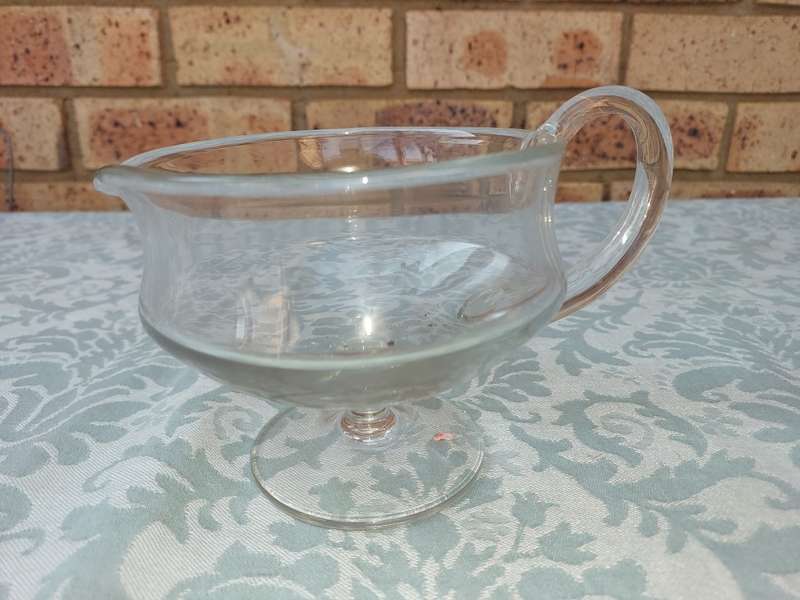 A GLASS SOUCE JUG SOLD AS IS