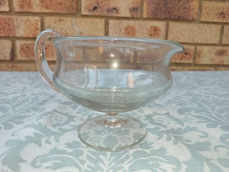 A GLASS SOUCE JUG SOLD AS IS