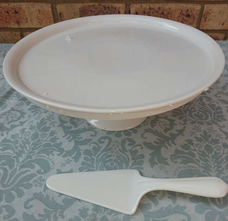 A JUST WHITE PORCELAIN EETRITE FOOTED CAKE STAND AND CUTTER