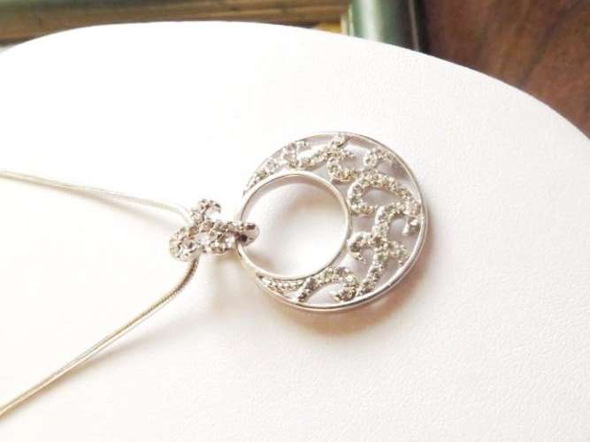A round pendant on a fleur-de-lis link con a silver tone chain