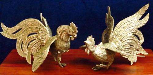A vintage pair of silver plated brass fighting roosters that could be ornaments or bookends