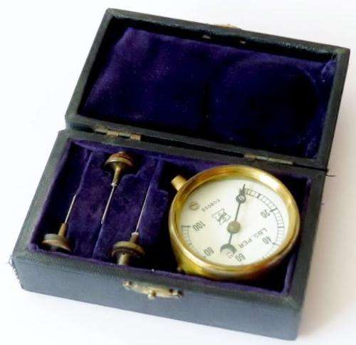 Small antique cast iron pressure gauge with brass plated trim in original case with 3 needles