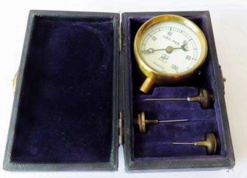 Small antique cast iron pressure gauge with brass plated trim in original case with 3 needles