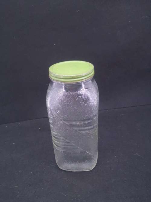 Old glass storage bottle with green tin lid