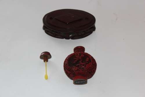 STUNNING CHINESE CINNABAR PORCELAIN SNUFF BOTTLE WITH HAND CARVED WOODEN BASE IN EXCELLENT CONDITION