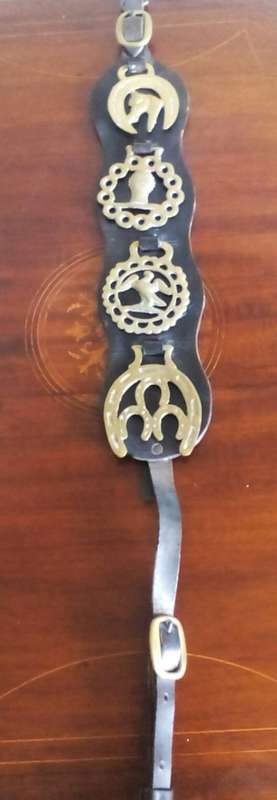 Vintage set of four horse brasses on leather strip.