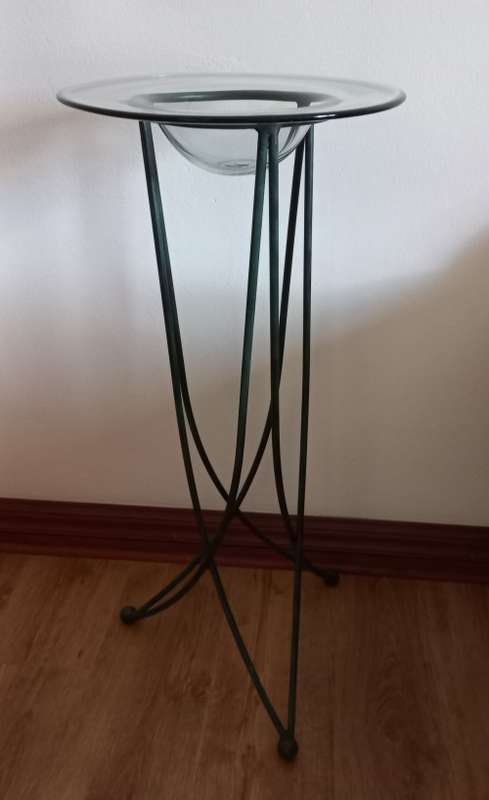 Ornamental stand with glass bowl on wrought-iron legs.