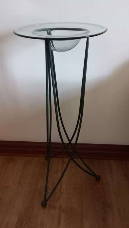 Ornamental stand with glass bowl on wrought-iron legs.