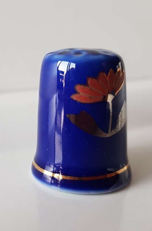 A Vintage collectors thimble. Thimble in blue glaze, painted flower in front