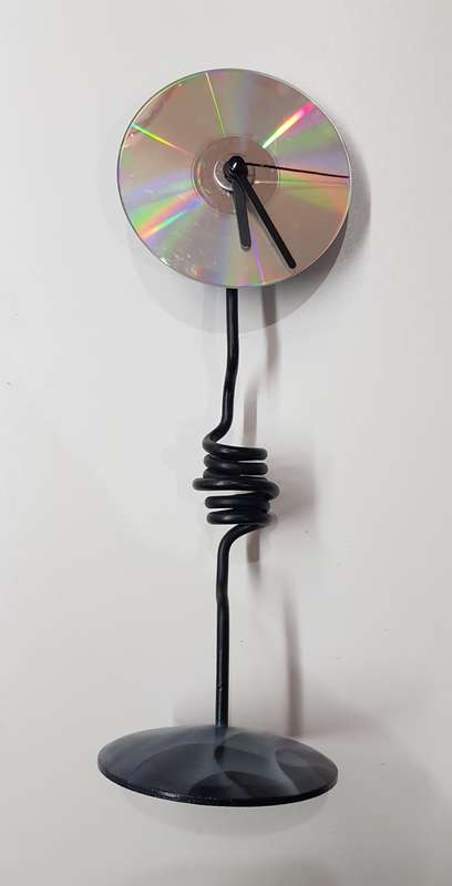 Desk standing clock, twisted iron with coloured base and a CD disc clock face.