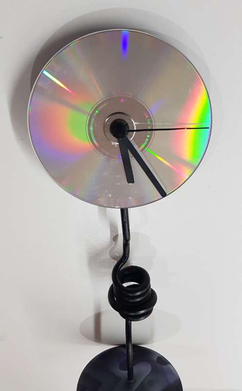 Desk standing clock, twisted iron with coloured base and a CD disc clock face.
