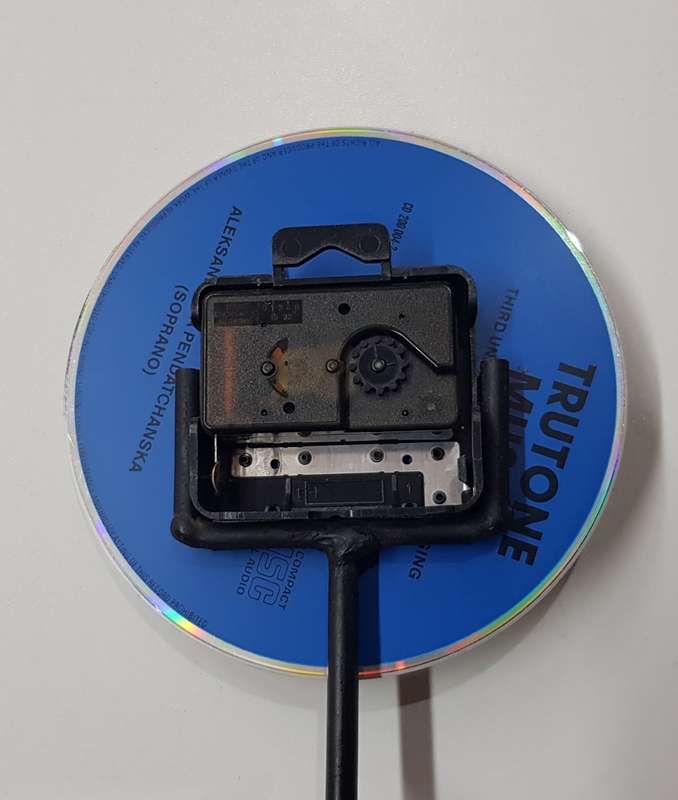 Desk standing clock, twisted iron with coloured base and a CD disc clock face.