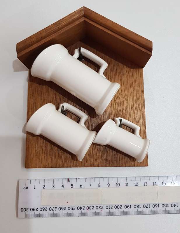 Vintage Dutch ceramic milk cans on hooks.
