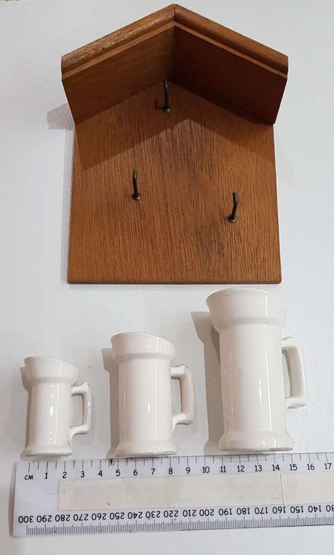 Vintage Dutch ceramic milk cans on hooks.