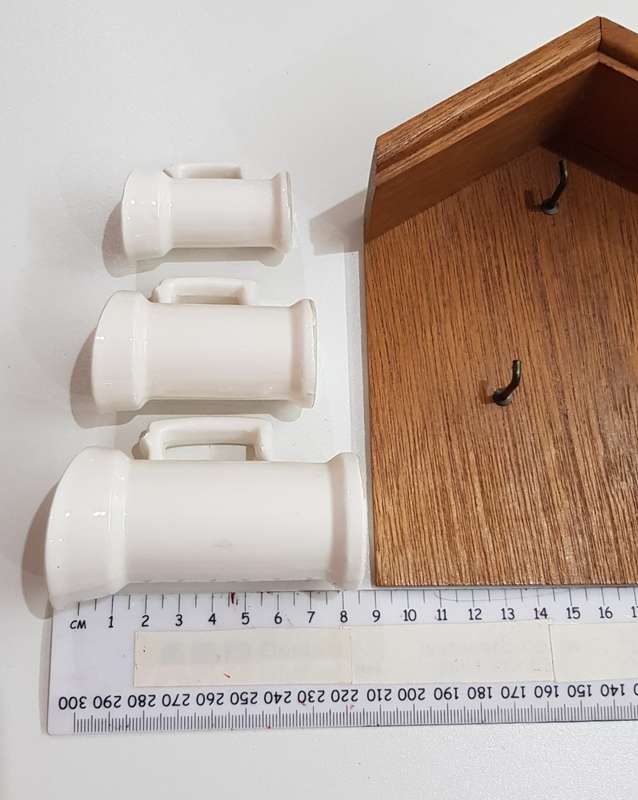 Vintage Dutch ceramic milk cans on hooks.
